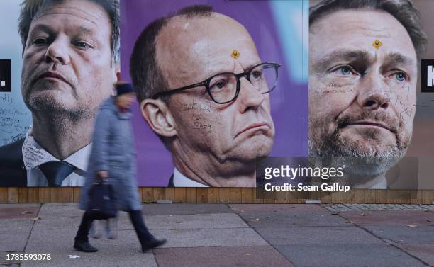 Woman walks past a tabloid newspaper billboard showing Economy Minister and Greens Party member Robert Habeck, German Christian Democrats head...