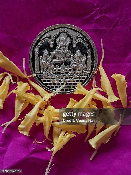 lord ganesh /goddess lakshmi/goddess saraswati silver coin on a pink paper with marigold flowers/dhanteras/diwali/deepavali festival - laxmi ganesh stock-fotos und bilder