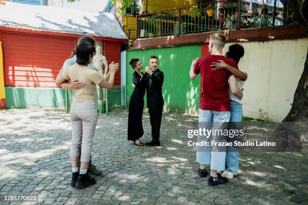 coppia di artisti di strada che ballano e insegnano il tango ai turisti su caminito, buenos aires, argentina - tango foto e immagini stock