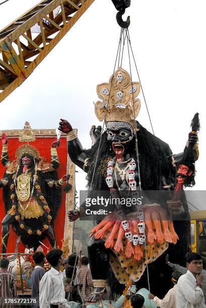 Huge idols of goddess kali are lifted by cranes for their immersion in the upper lake in Bhopal, 17 October 2002. Despite protests by...