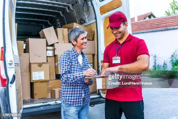 woman signing for her delivery from the courier - delivery person stock pictures, royalty-free photos & images