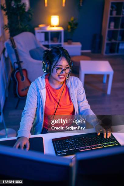 modern female gamer asian ethnicity playing video game on pc - flexible screen stock pictures, royalty-free photos & images
