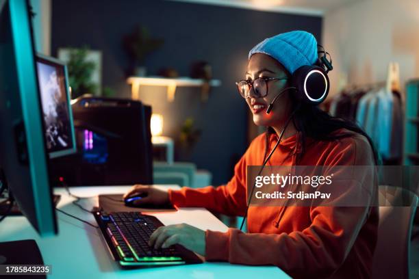 female gamer asian ethnicity, playing fps video game on computer - fair game stockfoto's en -beelden