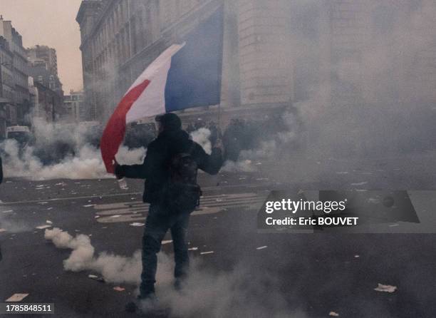 Manifestant avec un drapeau français au milieu de gaz lacrymogène lors de la manifestation des Gilets Jaunes le 5 décembre 2019 à Paris.