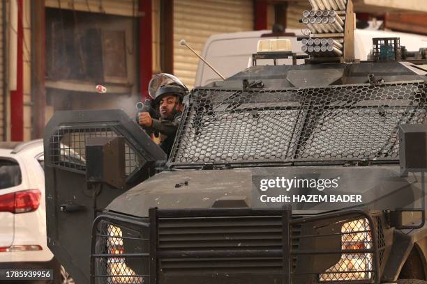An Israeli security force officer fires a sponge grenade as the army surrounds the area of a Palestinian home, believed to belong to one of the...