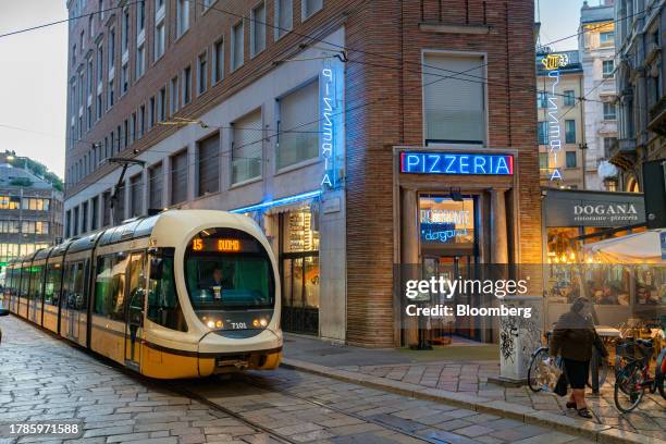 Tram passes by a Pizzeria in Via Cappellari near the Piazza Duomo in Milan, Italy, on Wednesday Nov. 15, 2023. A possible downgrade of Italy to junk...