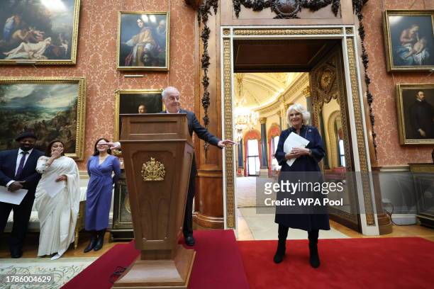 Queen Camilla reacts to Gyles Brandreth speaking as Dr Linda Yueh and other guests listen, during a reception at Buckingham Palace for winners of The...