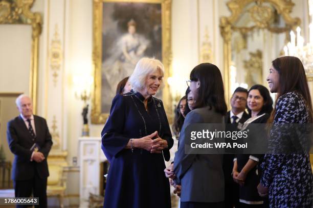 Queen Camilla speaks with Mitali Ragtah, junior runner-up as she hosts a reception at Buckingham Palace for winners of The Queen's Commonwealth Essay...