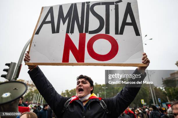 Protester holds a placard reading "no to amnesty" protesting outside the Congress of Deputies as the Parliamentary debate is being carried out for...