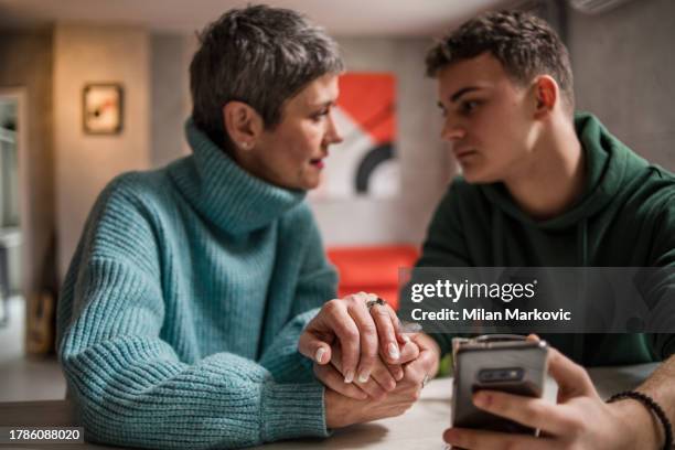 una madre e un figlio sono seduti a casa e parlano, aiutando il figlio a risolvere i suoi problemi adolescenziali - 18 19 anni foto e immagini stock