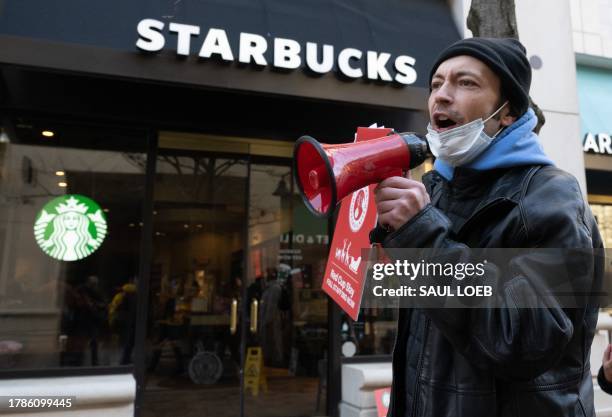 Former employees and supporters join unionized Starbucks employees as they carry signs in support of a strike, outside of a Starbucks store in...