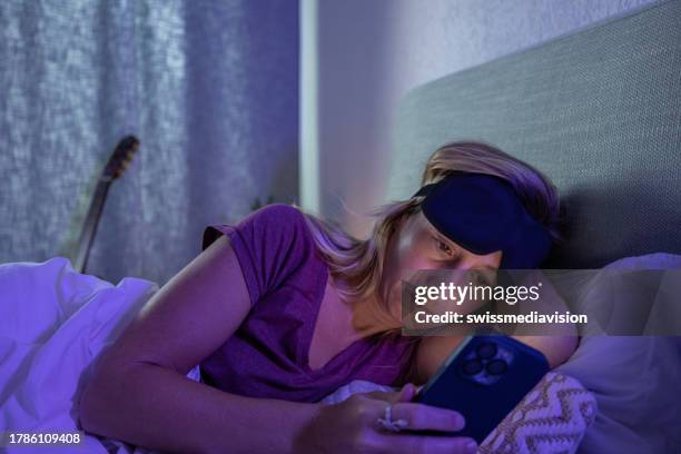 une femme alitée incapable de dormir utilise un téléphone portable - heure du coucher photos et images de collection