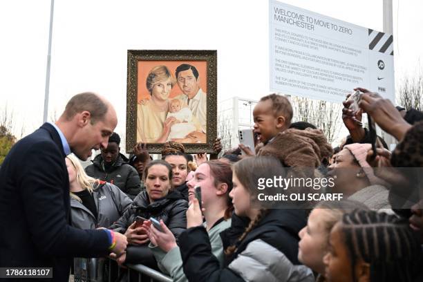Britain's Prince William, Prince of Wales meets with well-wishers as a member of the public holds a painting depicting late Britain's Diana, Princess...