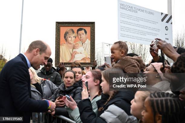 Britain's Prince William, Prince of Wales meets with well-wishers as a member of the public holds a painting depicting late Britain's Diana, Princess...