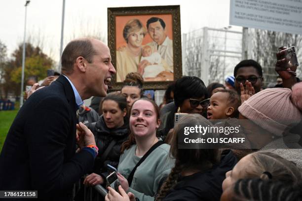 Britain's Prince William, Prince of Wales meets with well-wishers as a member of the public holds a painting depicting late Britain's Diana, Princess...