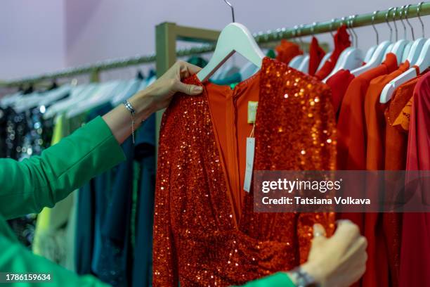 unrecognizable woman fashion enthusiast is immersed in the experience of choosing an elegant dress, surrounded by the allure of luxurious fabrics and timeless designs - red sequin dress stock pictures, royalty-free photos & images
