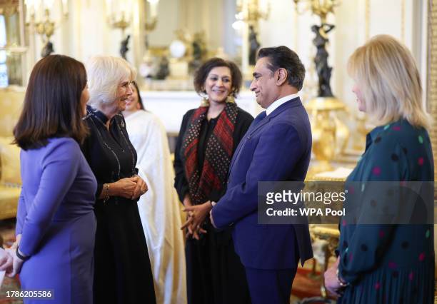 Queen Camilla speaks to Sanjeev Bhaska watched by Dame Joanna Lumley Meera Syal and Dr Linda Yueh as she hosts a reception at Buckingham Palace for...
