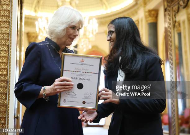 Queen Camilla poses with Siddhi Deshmukh, senior winner as she hosts a reception at Buckingham Palace for winners of The Queen's Commonwealth Essay...
