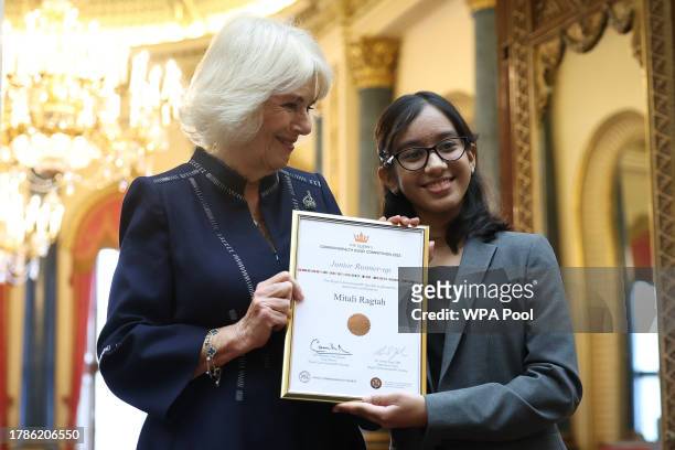 Queen Camilla poses with Mitali Ragtah, junior runner-up as she hosts a reception at Buckingham Palace for winners of The Queen's Commonwealth Essay...