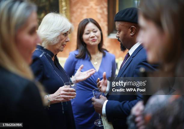 Queen Camilla speaks to Sir Ben Okri at a reception at Buckingham Palace for winners of The Queen's Commonwealth Essay Competition 2023 QCEC on...