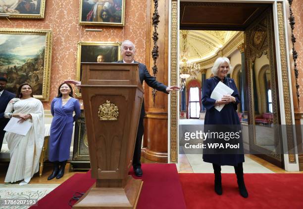 Queen Camilla reacts to Gyles Brandreth speaking as Dr Linda Yueh and other guests listen, during a reception at Buckingham Palace for winners of The...