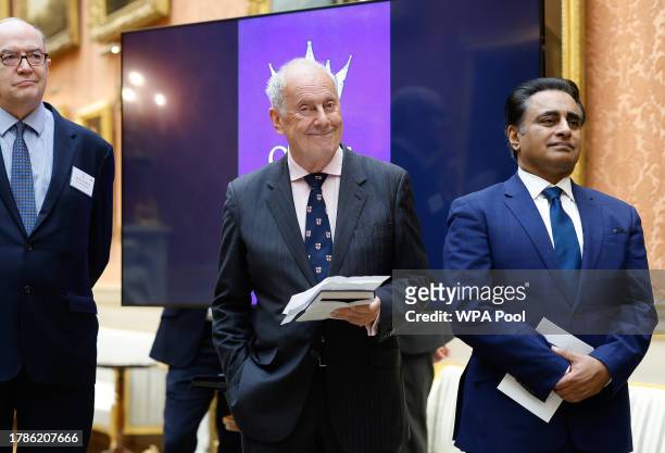 Gyles Brandreth smiles while standing next Sanjeev Bhaska to during a reception at Buckingham Palace for winners of The Queen's Commonwealth Essay...