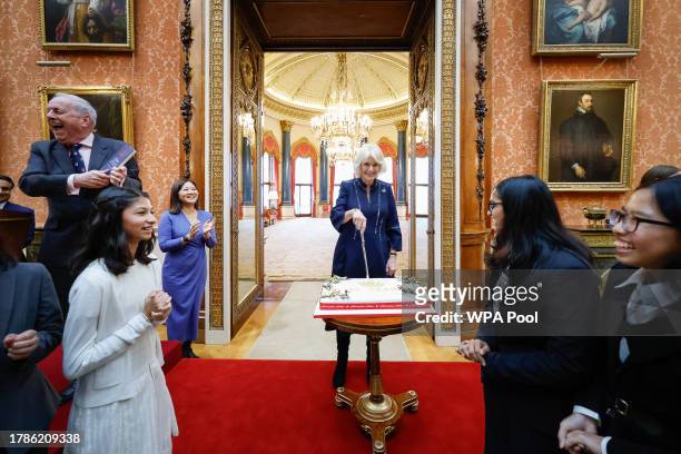 Queen Camilla cuts a cake in celebration of the 140th anniversary of The Queen's Commonwealth Essay Competition as she hosts a reception at...