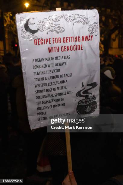 Pro-Palestinian protester holds up a sign bearing a 'Recipe For Getting Away With Genocide' during an Emergency Rally for Palestine outside...