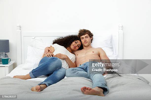 couple lying on bed together - zurücklehnen stock-fotos und bilder
