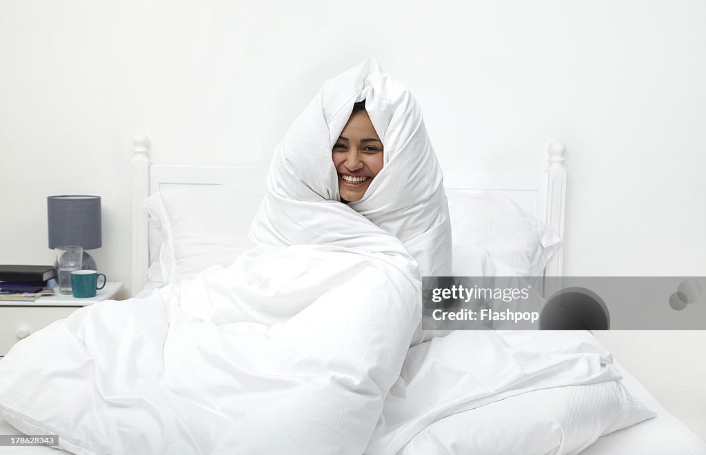 Woman wrapped in duvet laughing