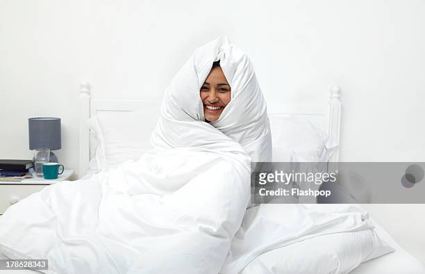 woman wrapped in duvet laughing - quilt imagens e fotografias de stock