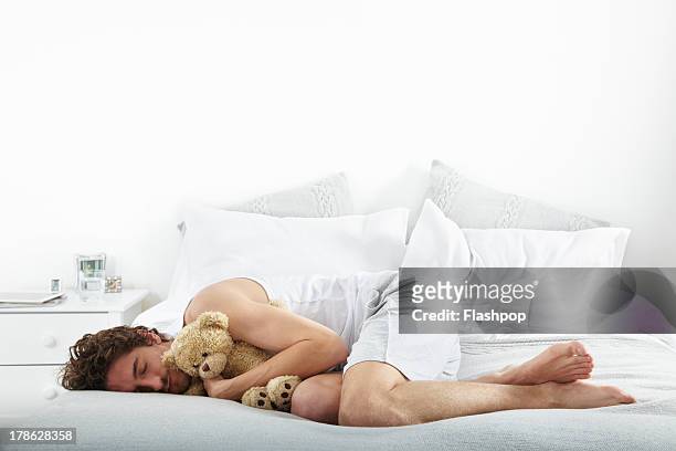 portrait of man lying on bed - position du foetus photos et images de collection
