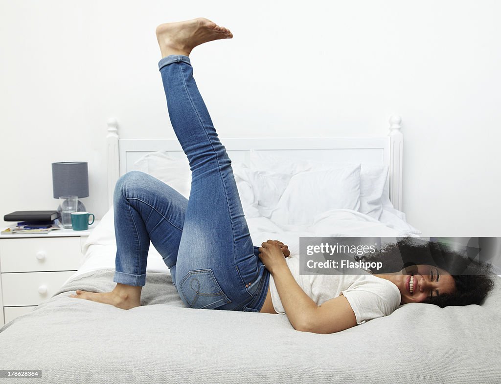 Woman lying on bed laughing
