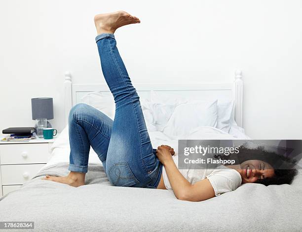woman lying on bed laughing - slaapkamer zijaanzicht stockfoto's en -beelden