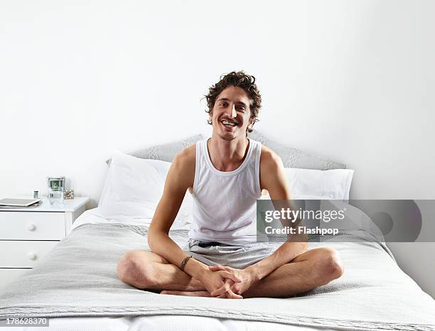 portrait of man sitting on bed - man in tank top stock pictures, royalty-free photos & images