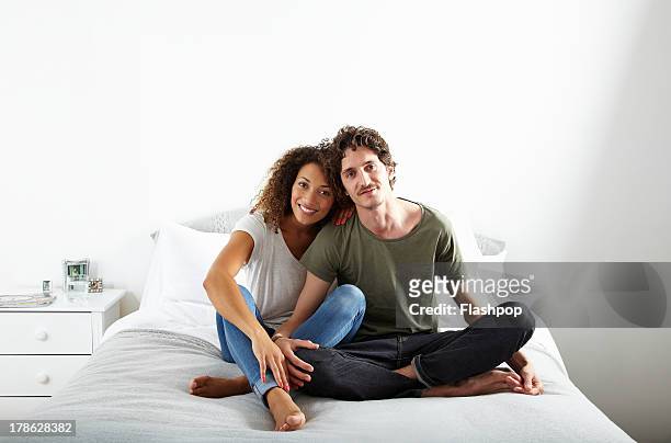 portrait of couple sitting on bed together - young man to bed photos et images de collection