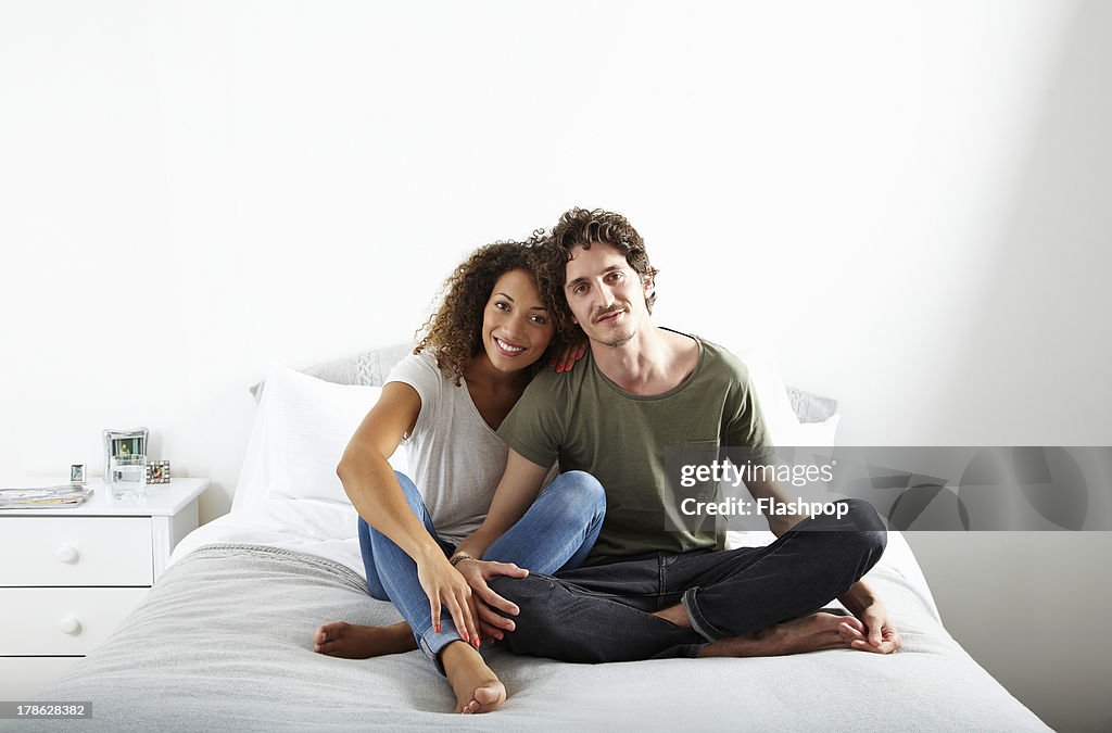Portrait of couple sitting on bed together