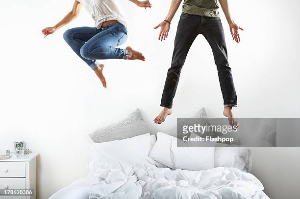 portrait of couple jumping on bed - jumping on bed stockfoto's en -beelden