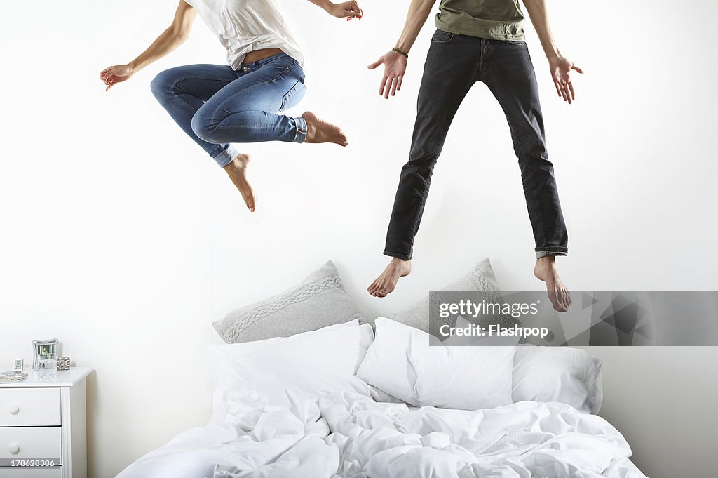 Portrait of couple jumping on bed