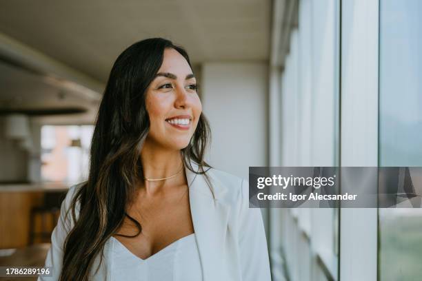 contemplative businesswoman looking in the window - mid adult women stock pictures, royalty-free photos & images