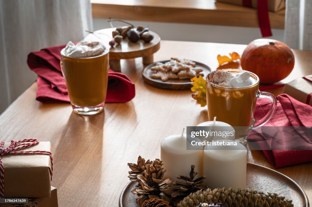 Still life of Christmas cozy home with two mugs of pumpkin spice latte with whipped cream against the window sill