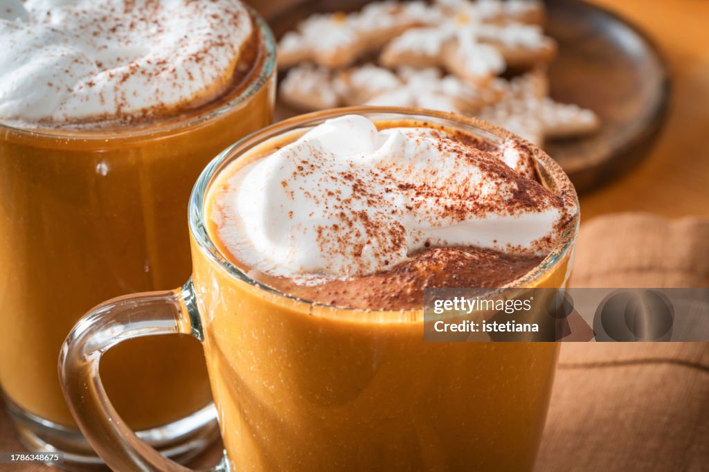 Still life of Christmas cozy home with two mugs of pumpkin spice latte with whipped cream
