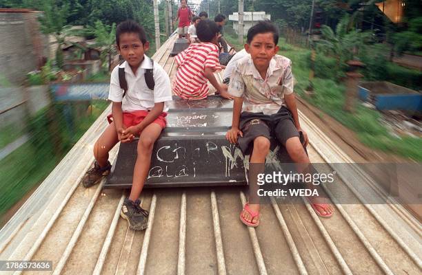 In the absence of security measures and a shortage of cheap public transportation, schoold children hike a ride on the roof of a commuter train...