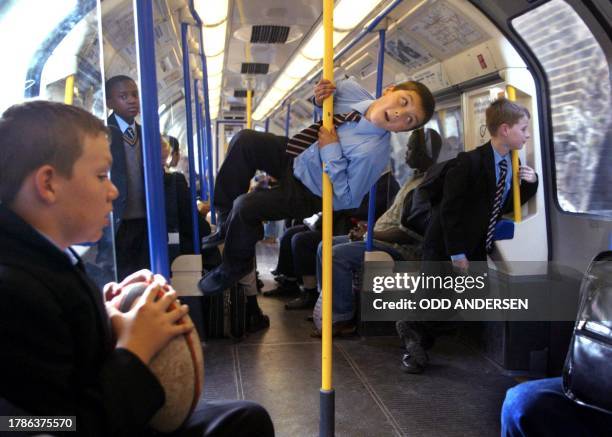 Youngster in his school uniform entertains friends 12 September 2001 while riding on an eastbound Picadilly line underground train in west London....