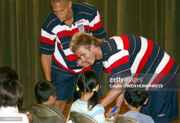 Rio Ferdinand and David Beckham sign autographs 10 June 2002 during a visit by the England players to the Ishya Elementary school near the team's...
