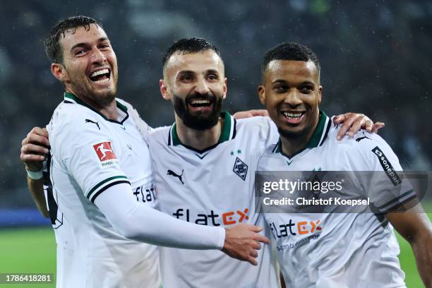 Alassane Plea of Borussia Moenchengladbach celebrates with teammates Joe Scally and Franck Honorat after scoring the team's fourth goal during the...