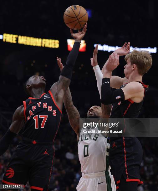 Toronto Raptors guard Dennis Schroder hauls in a rebound as Milwaukee Bucks guard Damian Lillard and Toronto Raptors guard Gradey Dick watch as the...