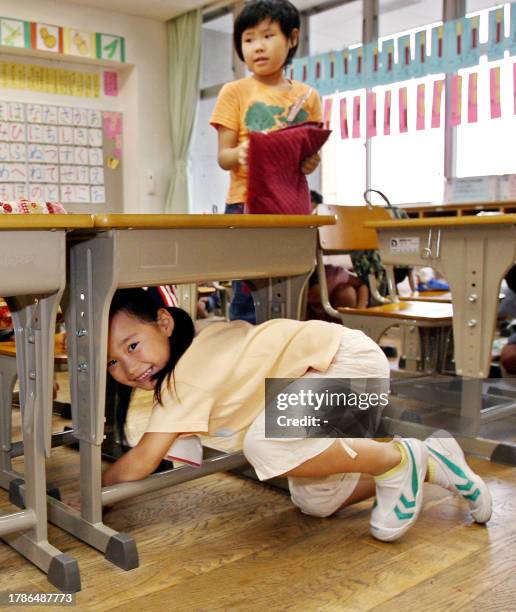 Elementary school children crouch under their desks as part of a nationwide earthquake drill at a Tokyo elementary school, 01 September 2006. Nearly...