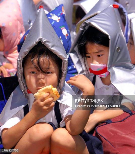 Wearing flame-proof hoods and covering their mouths with handkerchieves, pupils of the Tsukiji Elementary School wait in line for their parents as...