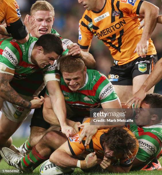 Matt Bell of the Tigers is tackled by George Burgess, Luke Burgess, Thomas Burgess and Sam Burgess of the Rabbitohs during the round 25 NRL match...